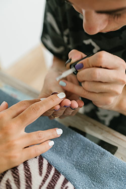 Manucuriste en train de poser du vernis, studio cils et ongles professionnel.