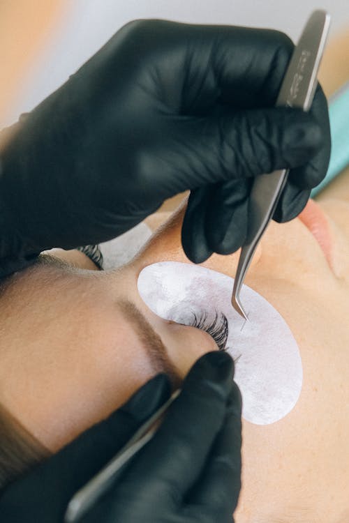 Pose d'extensions de cils au studio, gros plan sur la précision de la technicienne.