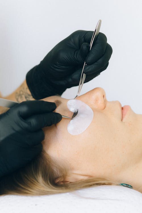 Pose d'extensions de cils en salon de beauté, gros plan sur les yeux.