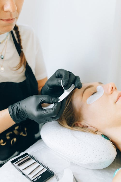Cliente allongée en salon de beauté, soins et entretien des extensions de cils après prestation